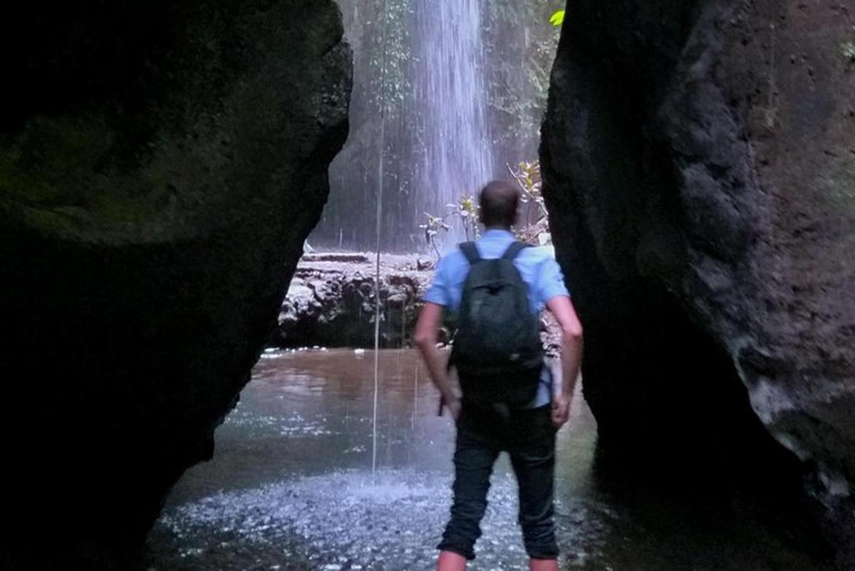 seorang pria berdiri di air di depan air terjun