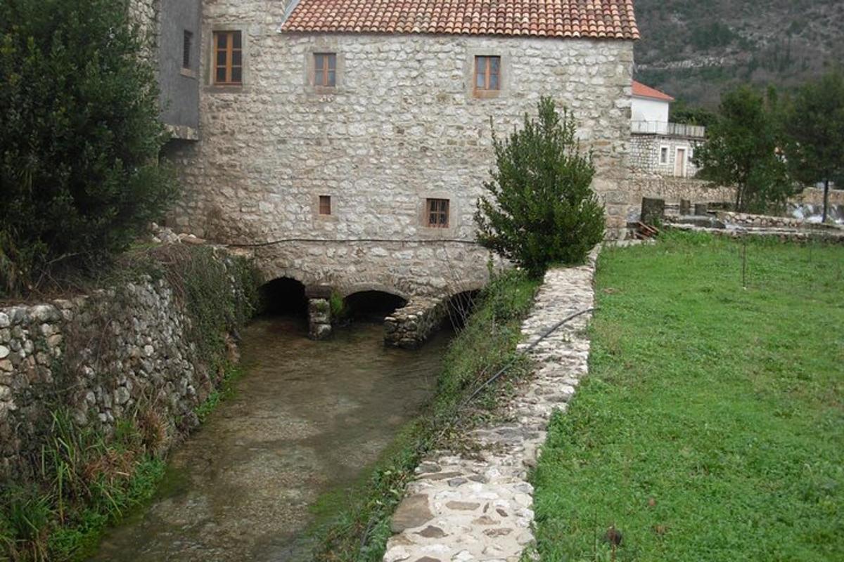 an old stone building with a river in front of it