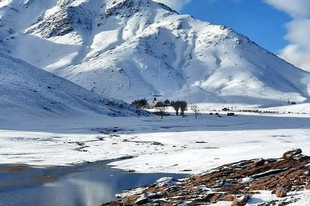 una montagna coperta di neve con un riflesso in uno specchio d'acqua