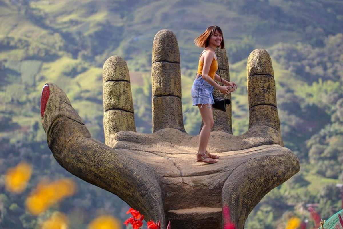 a young girl standing on the top of a statue of a hand