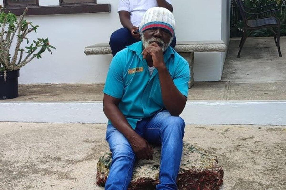 um homem sentado em uma pedra com a mão na boca