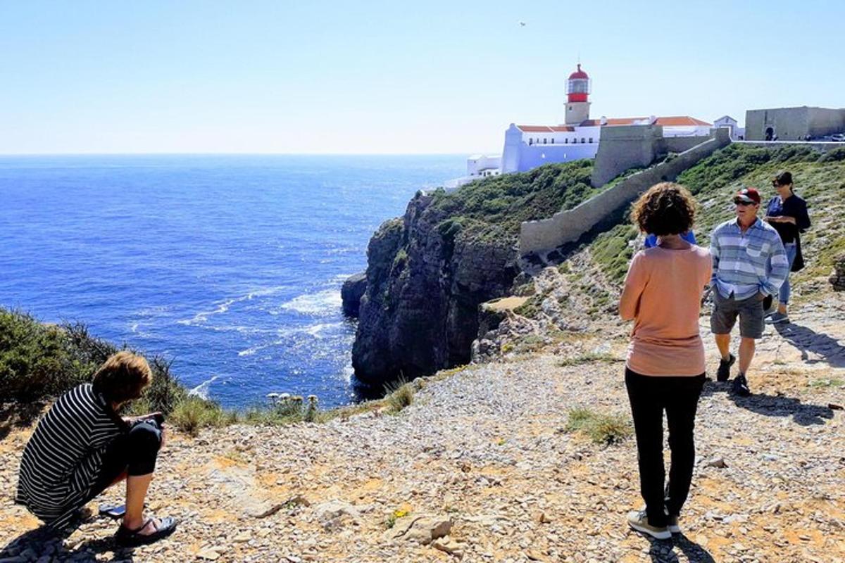 μια ομάδα ανθρώπων που περπατούν σε έναν βραχώδη λόφο με έναν φάρο