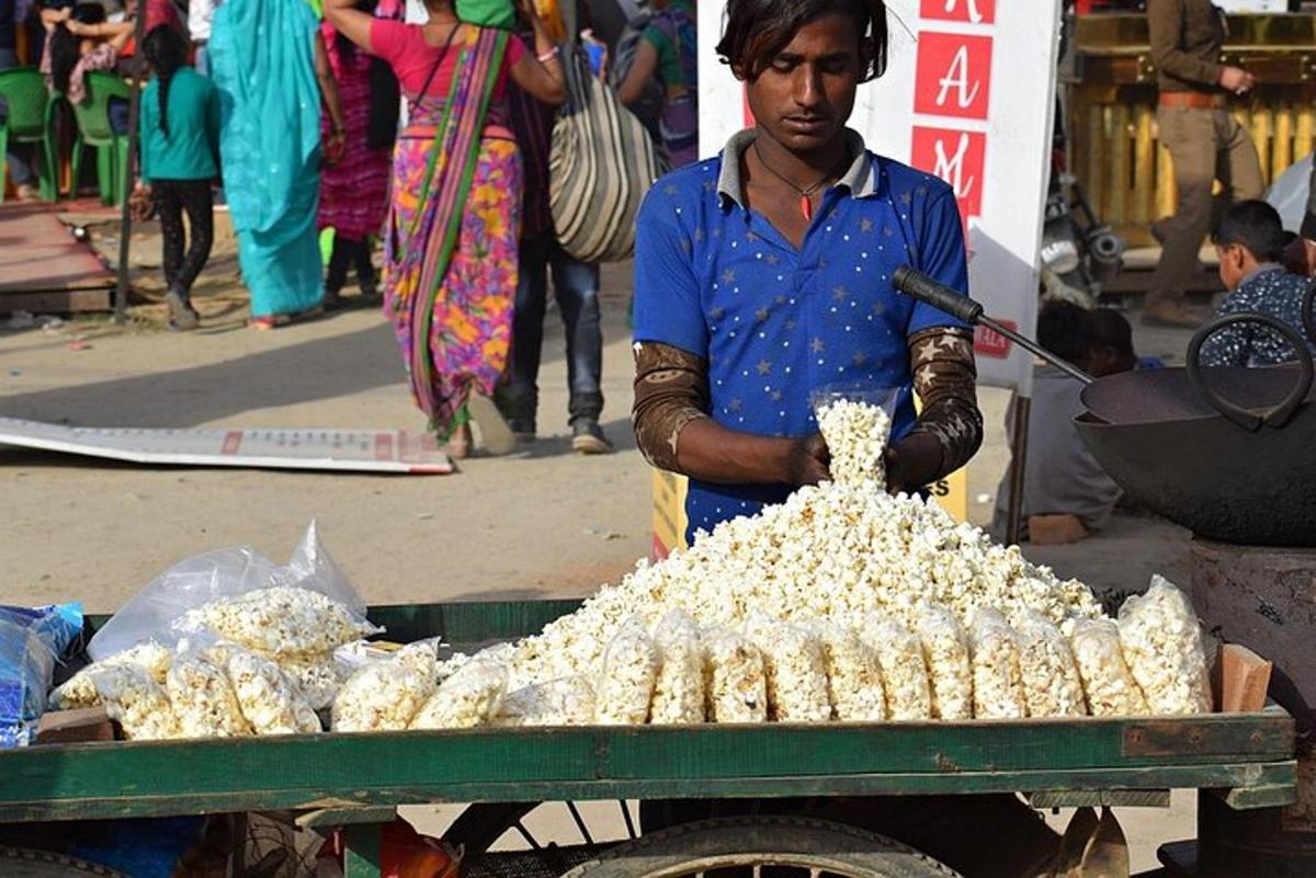 a man standing next to a cart filled with peanuts