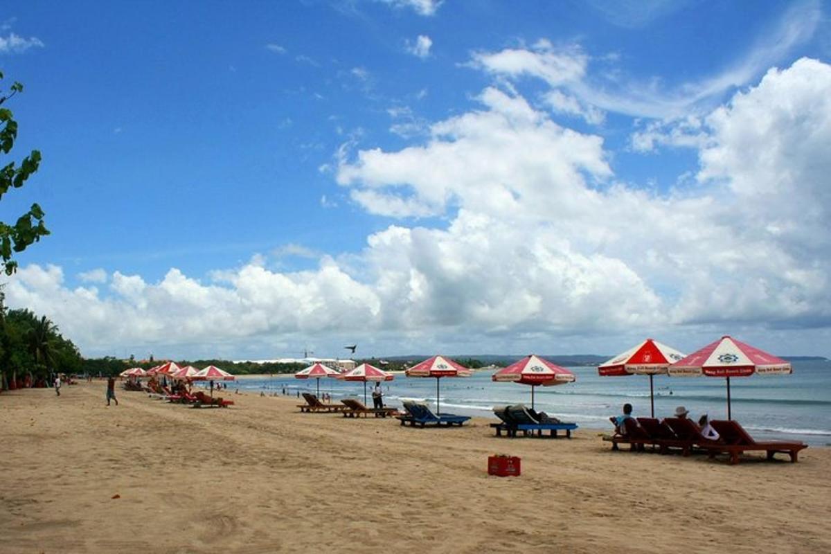 gent asseguda a la platja amb para-sols i l'oceà