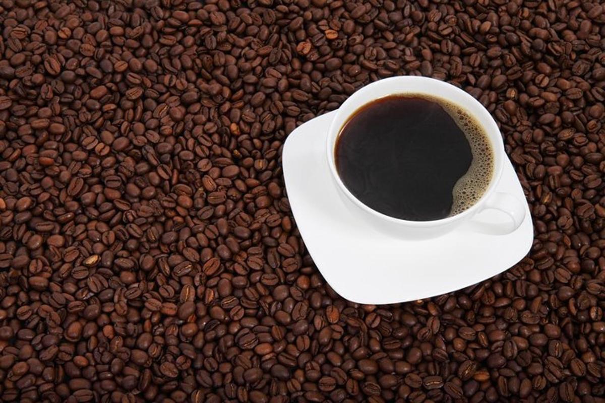 o ceașcă de cafea așezată pe o grămadă de boabe de cafea