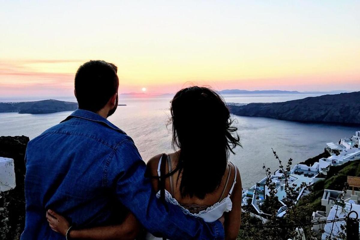 un bărbat și o femeie stând pe vârful unui deal cu vedere la ocean