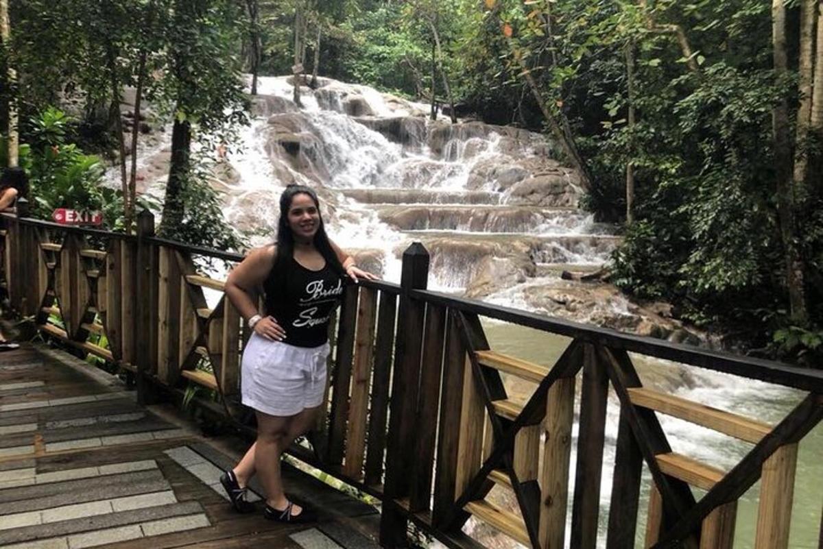 uma mulher parada em uma ponte em frente a uma cachoeira