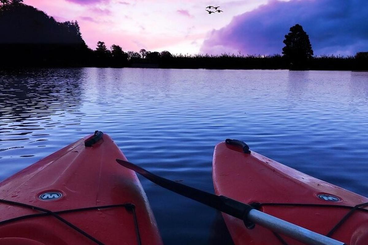 un parell de caiacs en un llac a la posta de sol