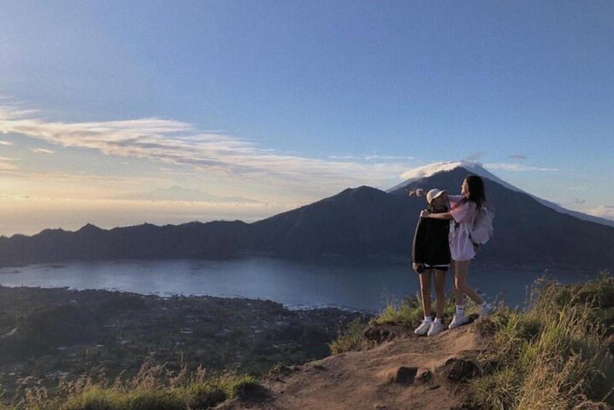Zwei Menschen stehen auf einem Hügel und schauen auf einen Berg