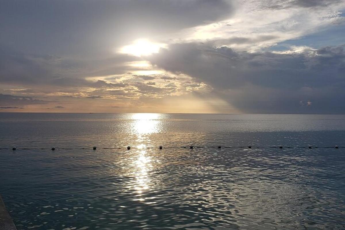 un grup de persones nedant a l'oceà a la posta de sol