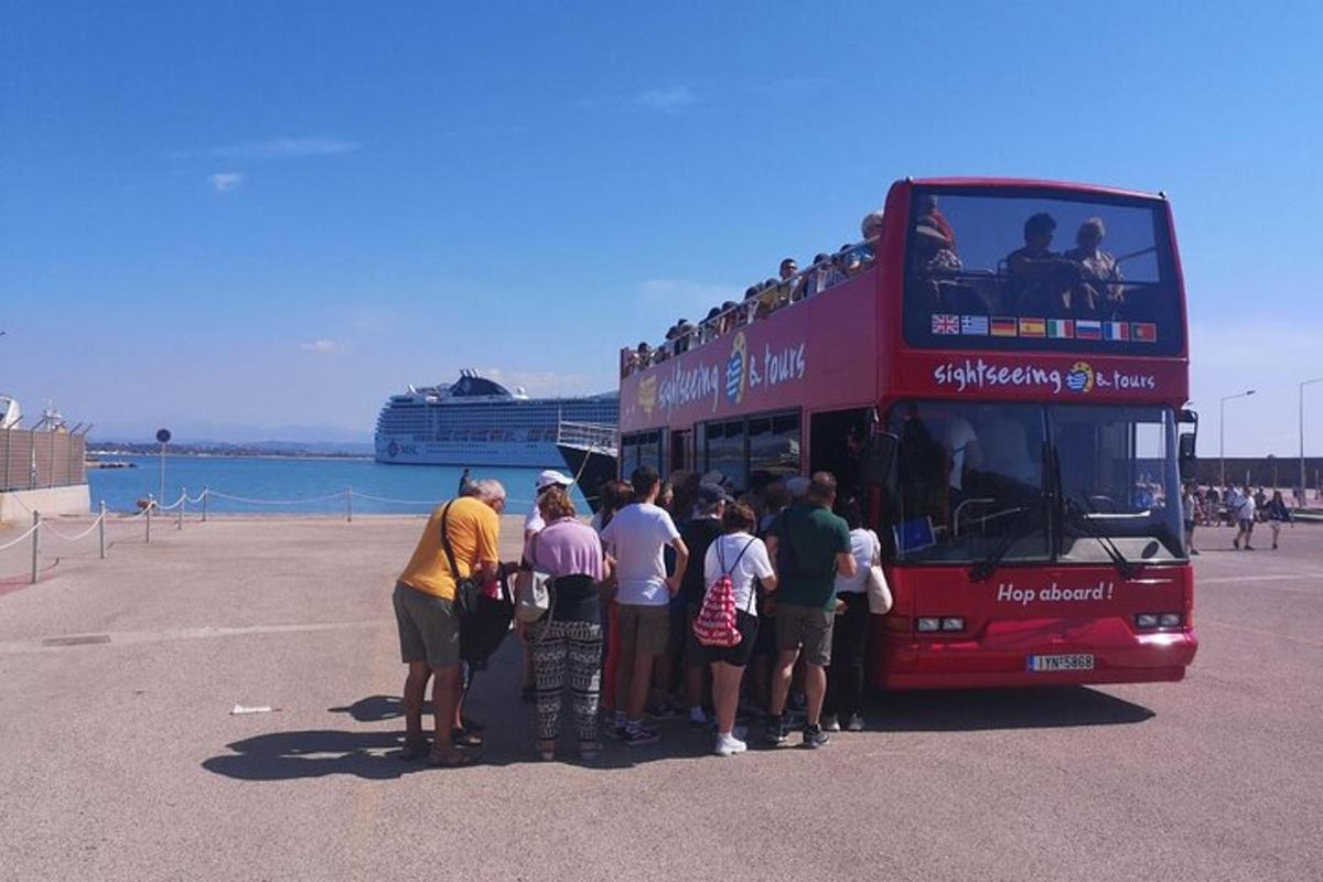 um grupo de pessoas em pé na frente de um ônibus de dois andares