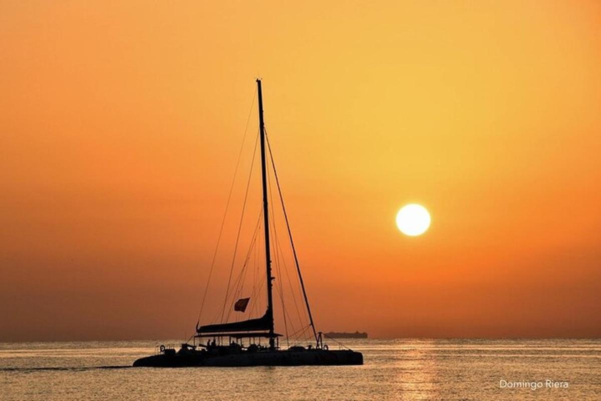 a sail boat in the water at sunset