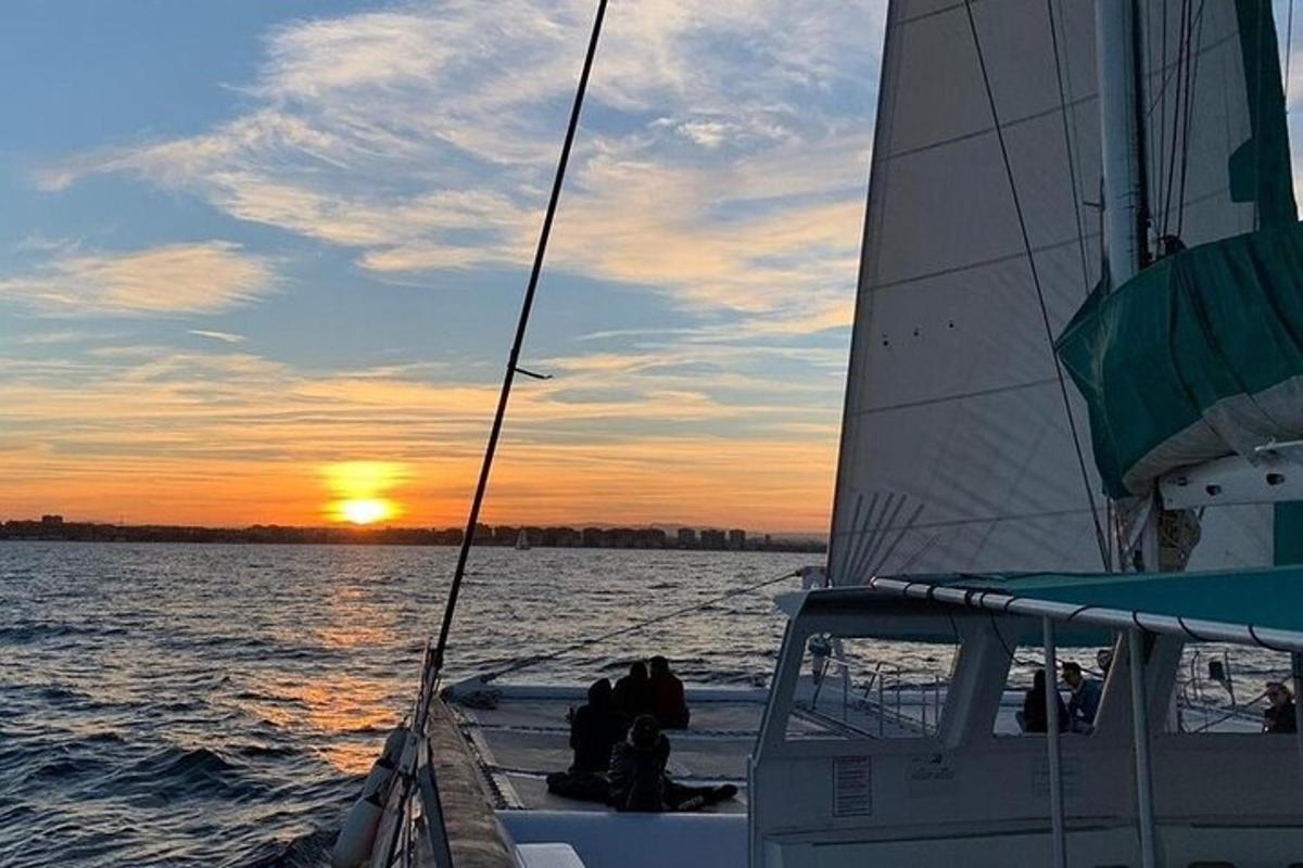 a group of people sitting on a sail boat at sunset
