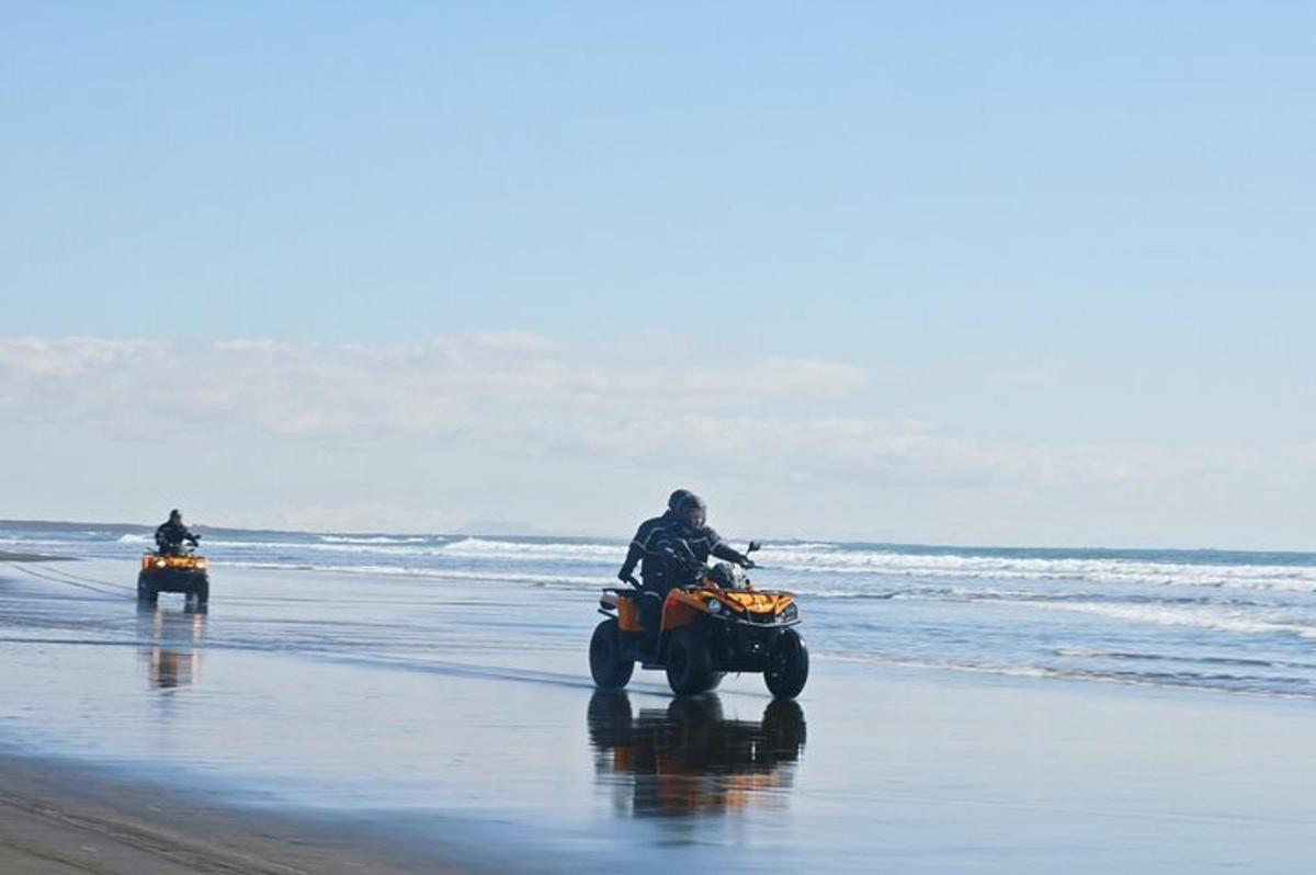 duas pessoas andando de quadriciclo na praia