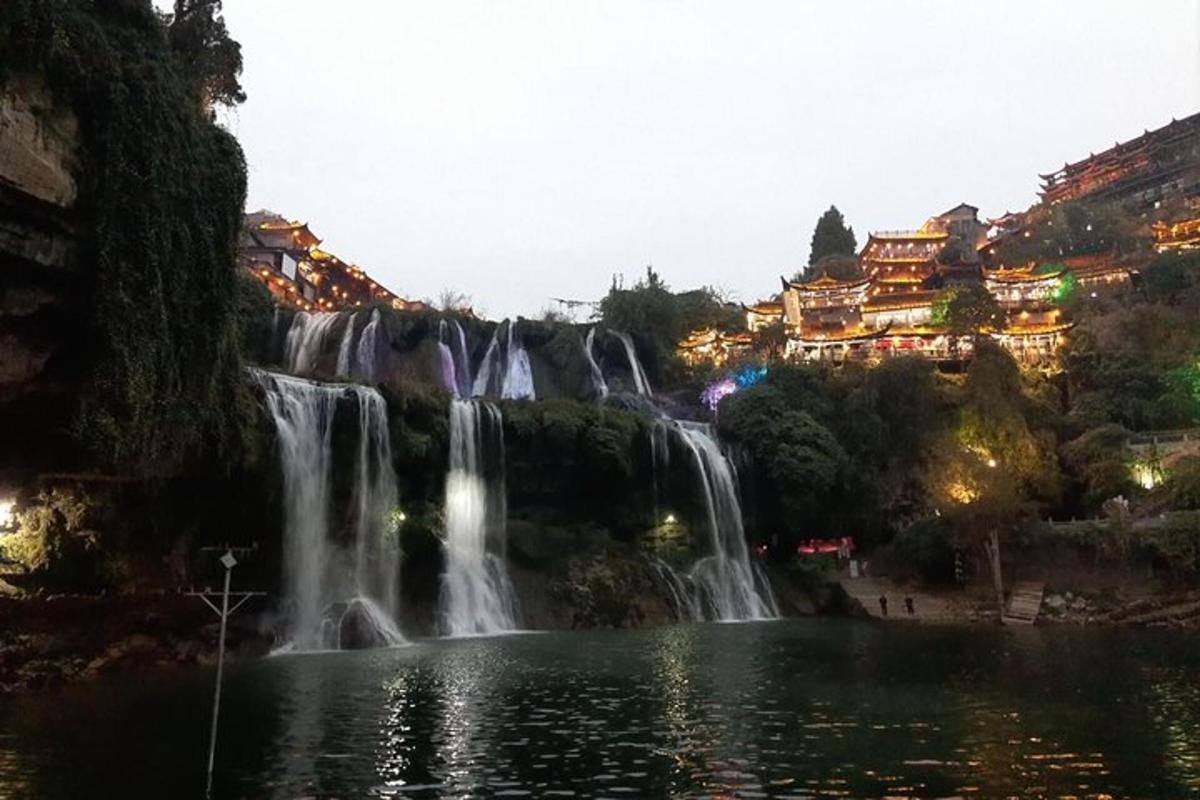 a waterfall over a pond in front of a city