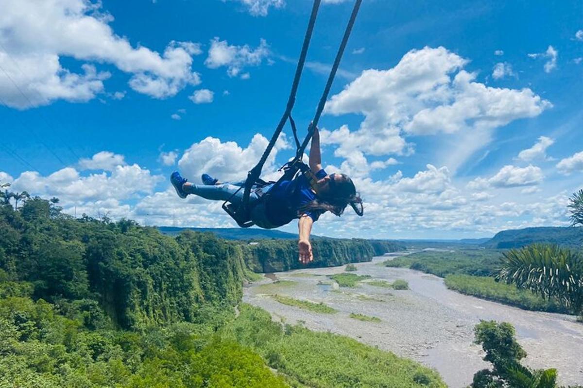 a person is hanging in the air over a river
