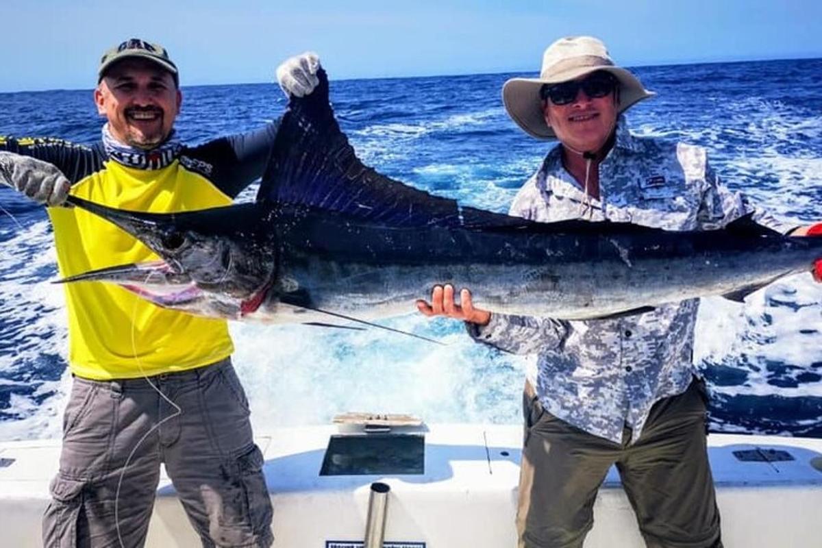 two men on a boat holding a large fish