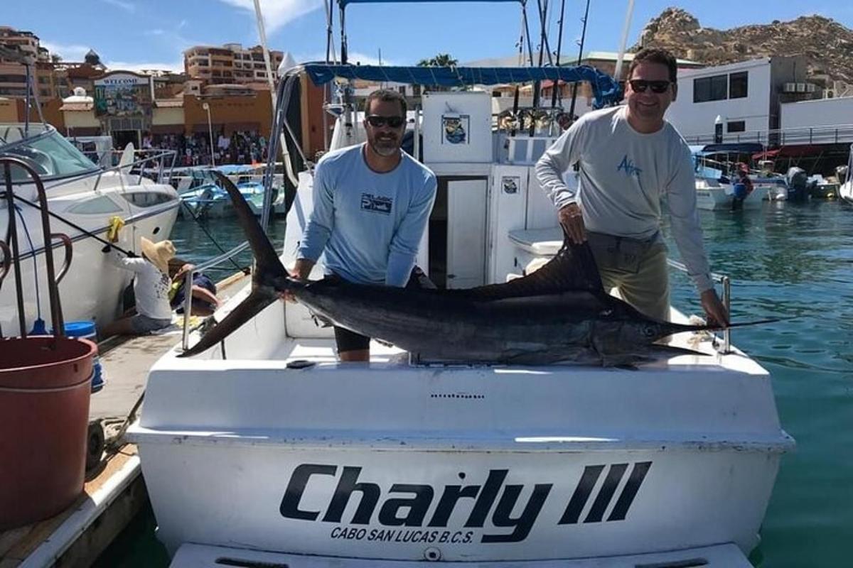 two men holding a fish on a boat