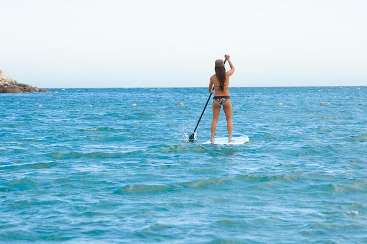 žena stojící na paddleboardu v oceánu