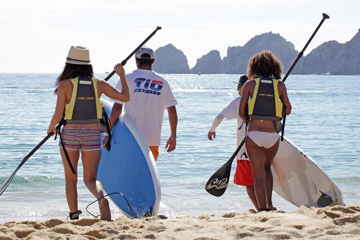 skupina lidí na pláži s paddleboardy