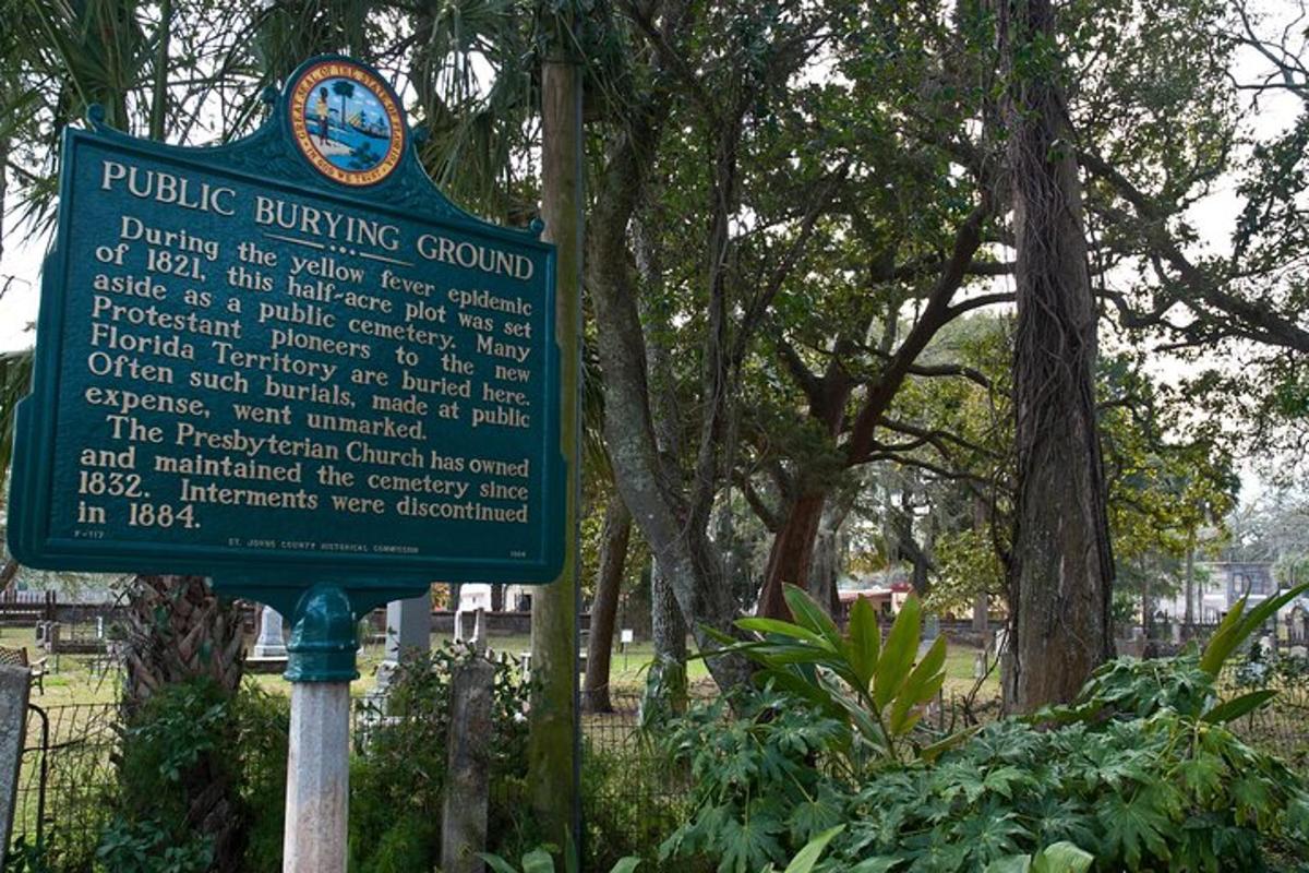 ein Schild in einem Park mit Bäumen im Hintergrund