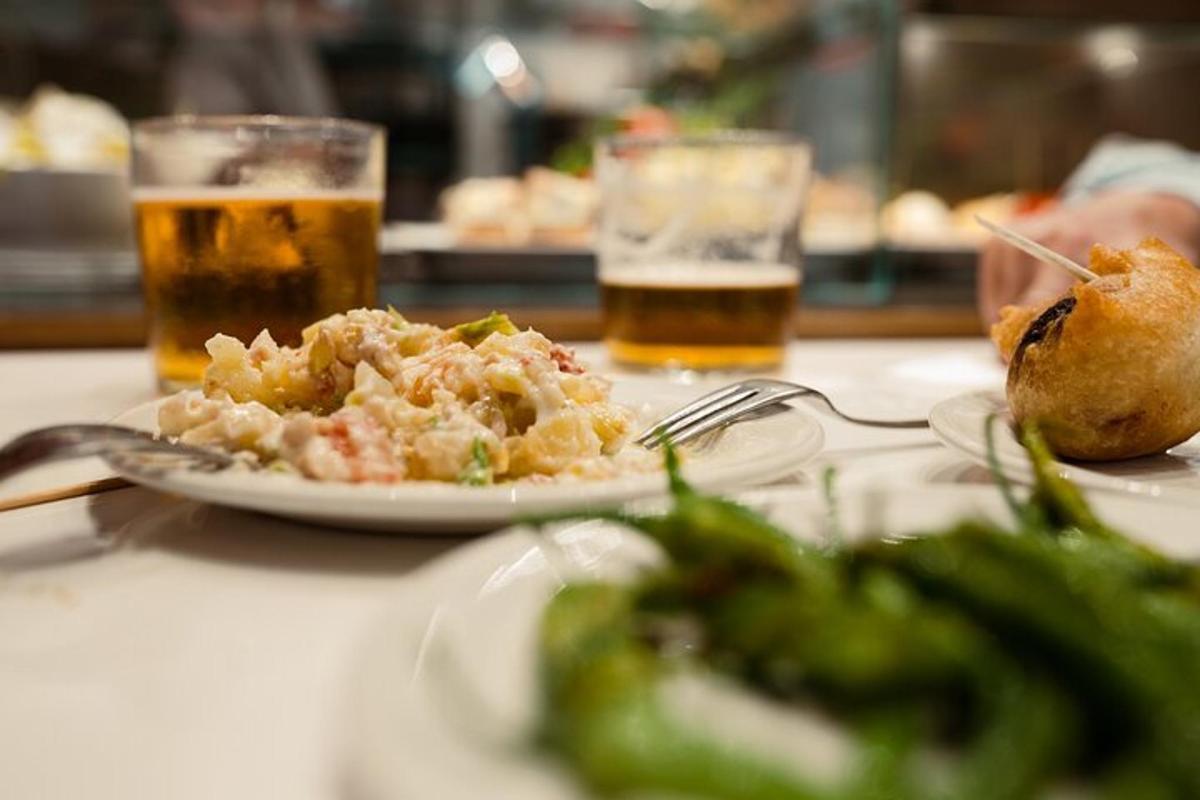 isang mesa na may isang plato ng pagkain at dalawang baso ng beer