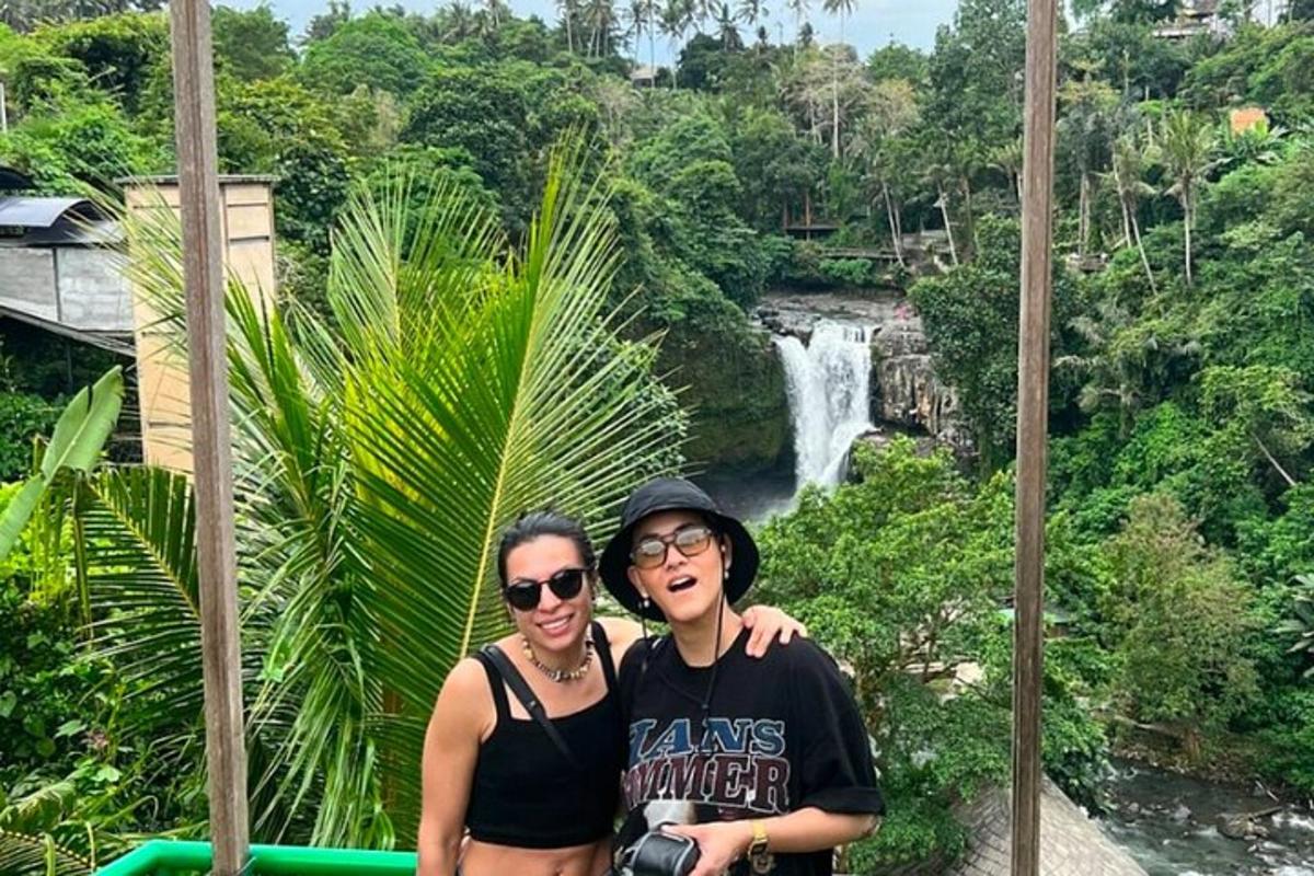 a man and woman standing in front of a waterfall