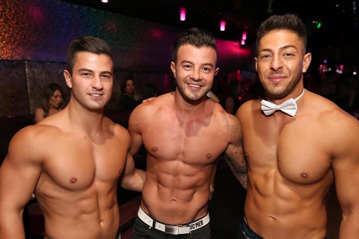 tre uomini a torso nudo che posano per una foto in un club