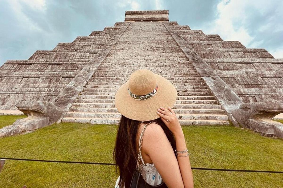 a woman in a hat standing in front of a pyramid