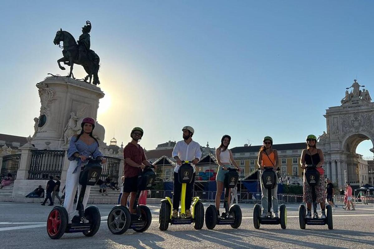 Skupina lidí jedoucích na segwayích před sochou