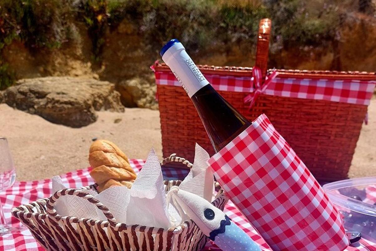 uma garrafa de vinho em uma cesta sobre uma toalha de piquenique