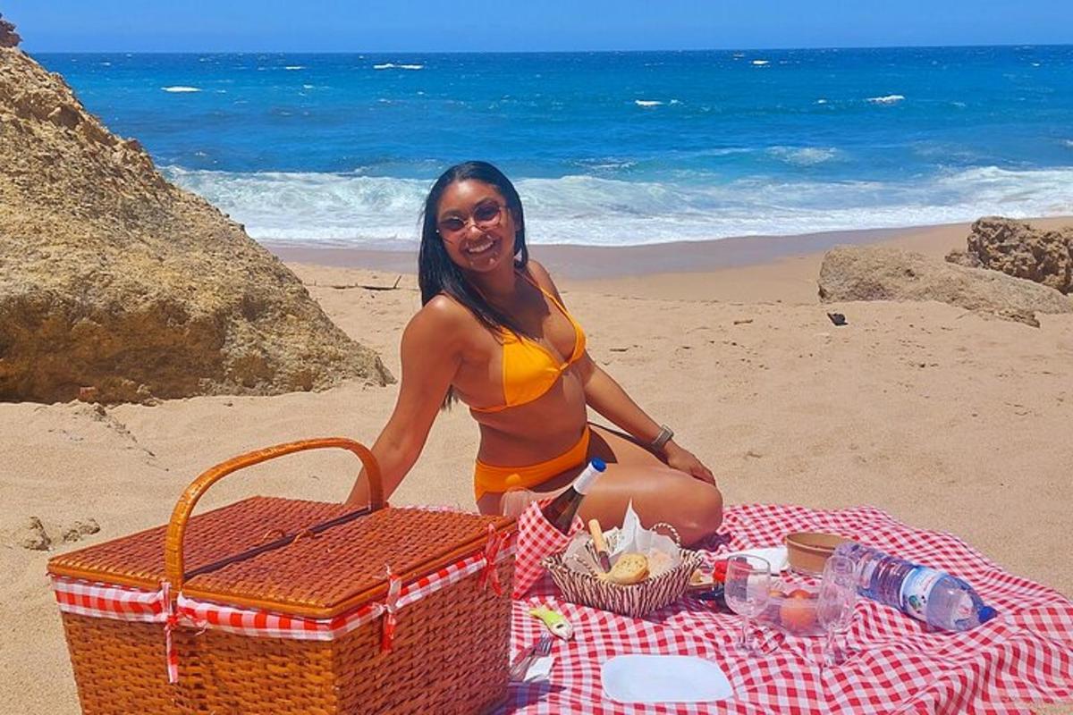 a woman sitting on a picnic blanket on the beach