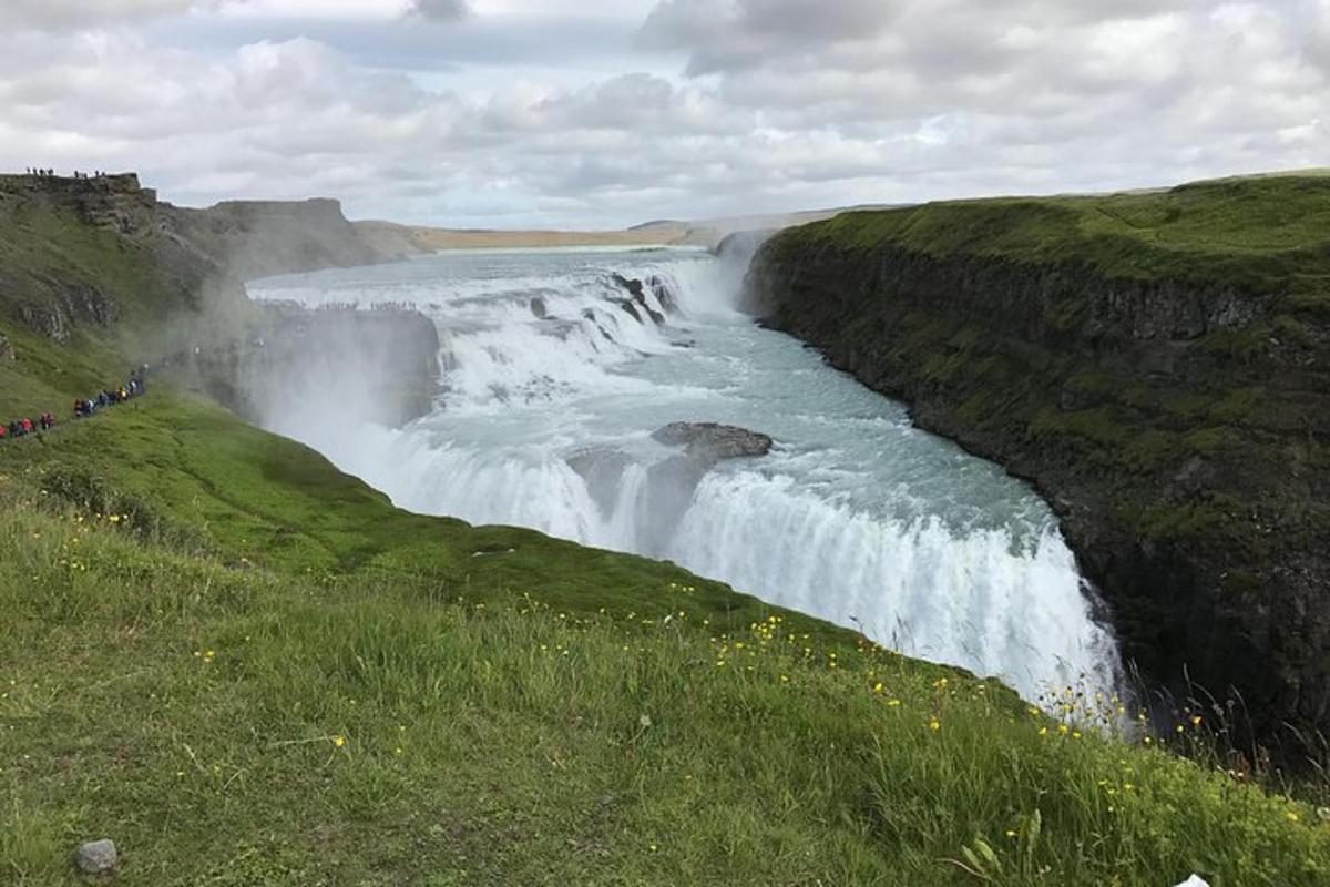 ein Wasserfall an der Seite eines Hügels neben einem Feld