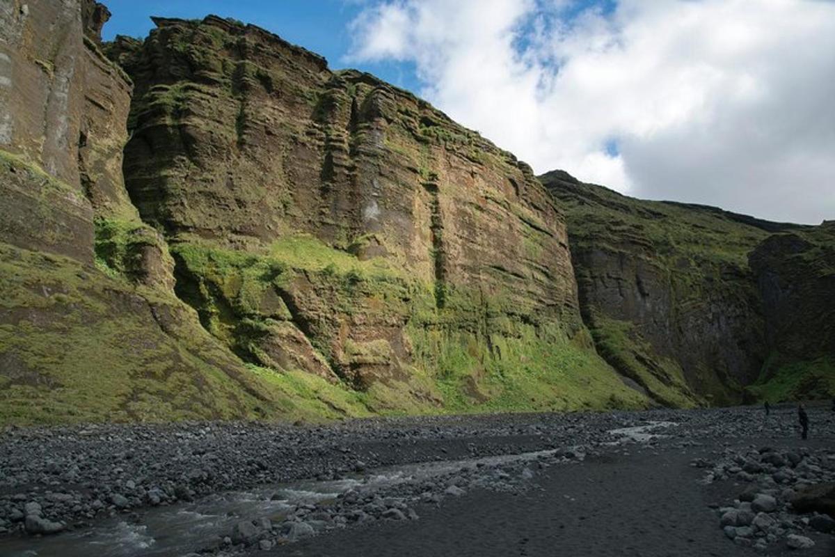 una collina rocciosa con un fiume di fronte