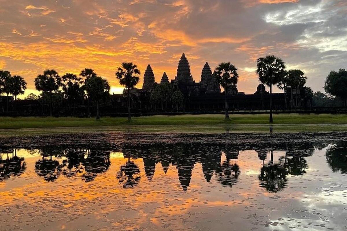 matahari terbenam di atas kolam dengan kuil di latar belakang