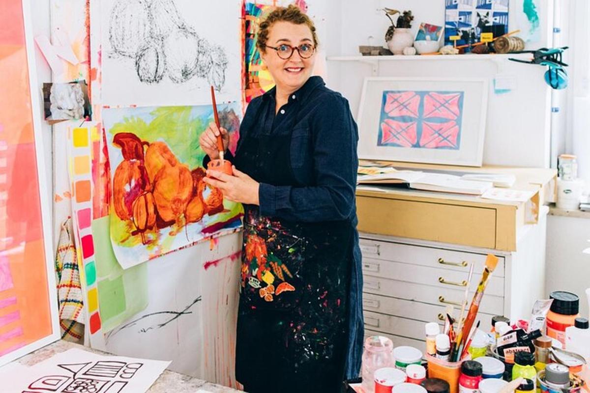 a woman standing in a room with a painting
