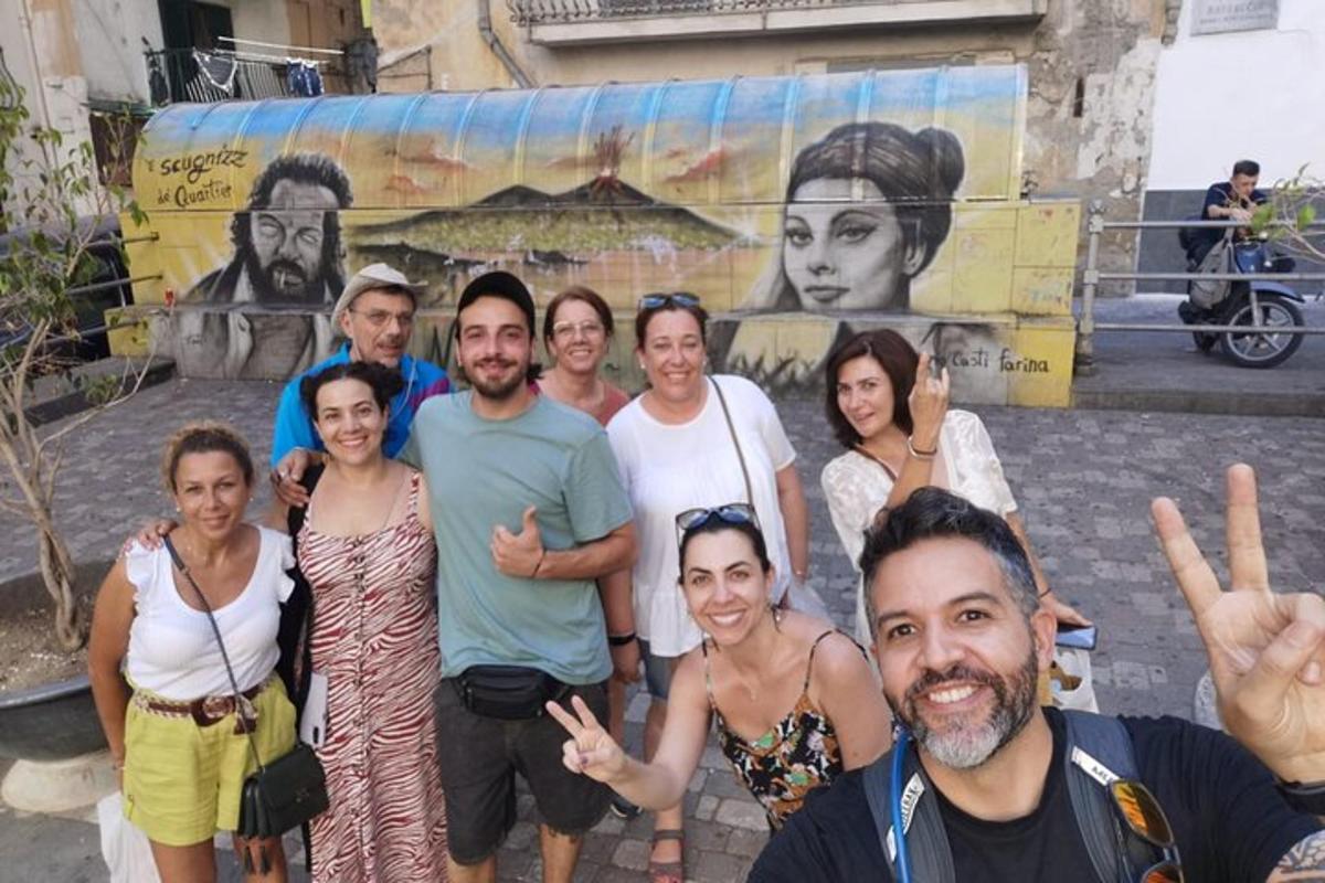 un gruppo di persone in piedi davanti a un murale
