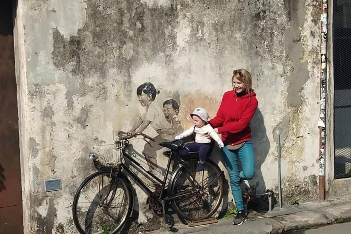 a woman and a child sitting on a bike next to a wall