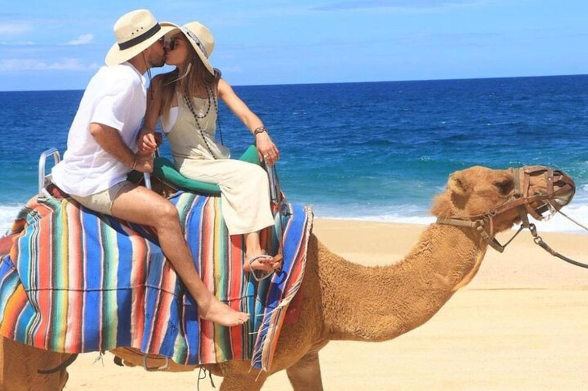 mężczyzna i kobieta jadący na wielbłądzie po plaży