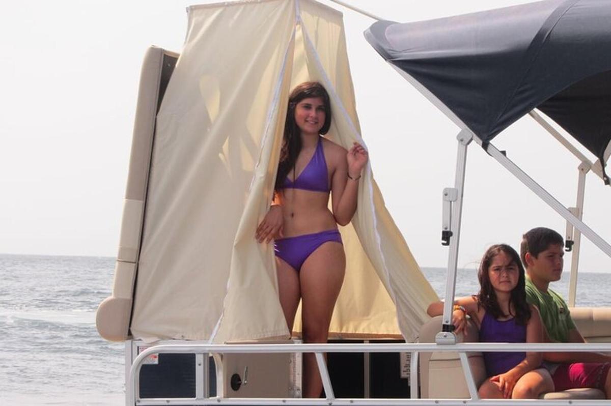 žena v bikinách stojící na zadní straně lodi