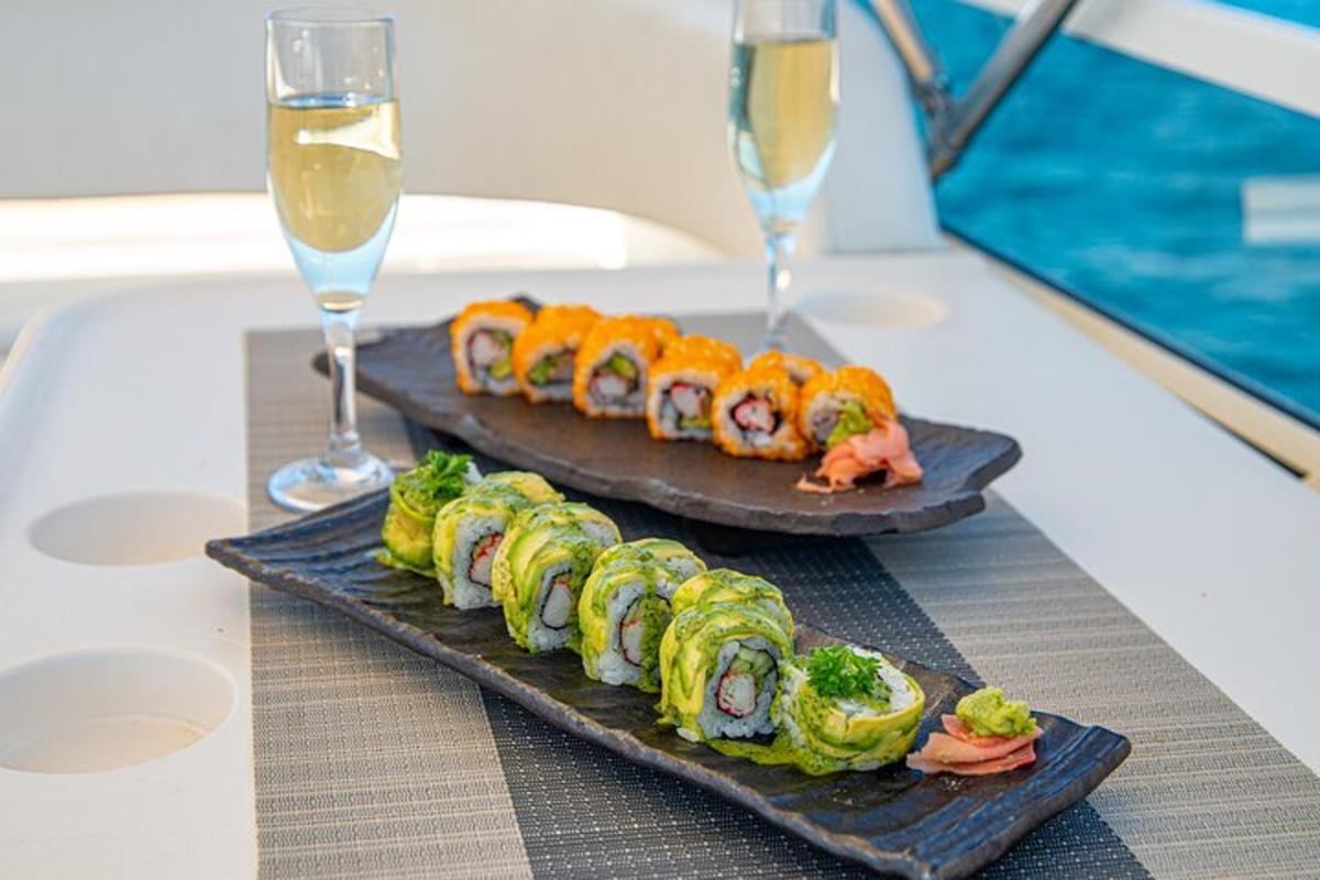 two plates of sushi on a table with glasses of wine