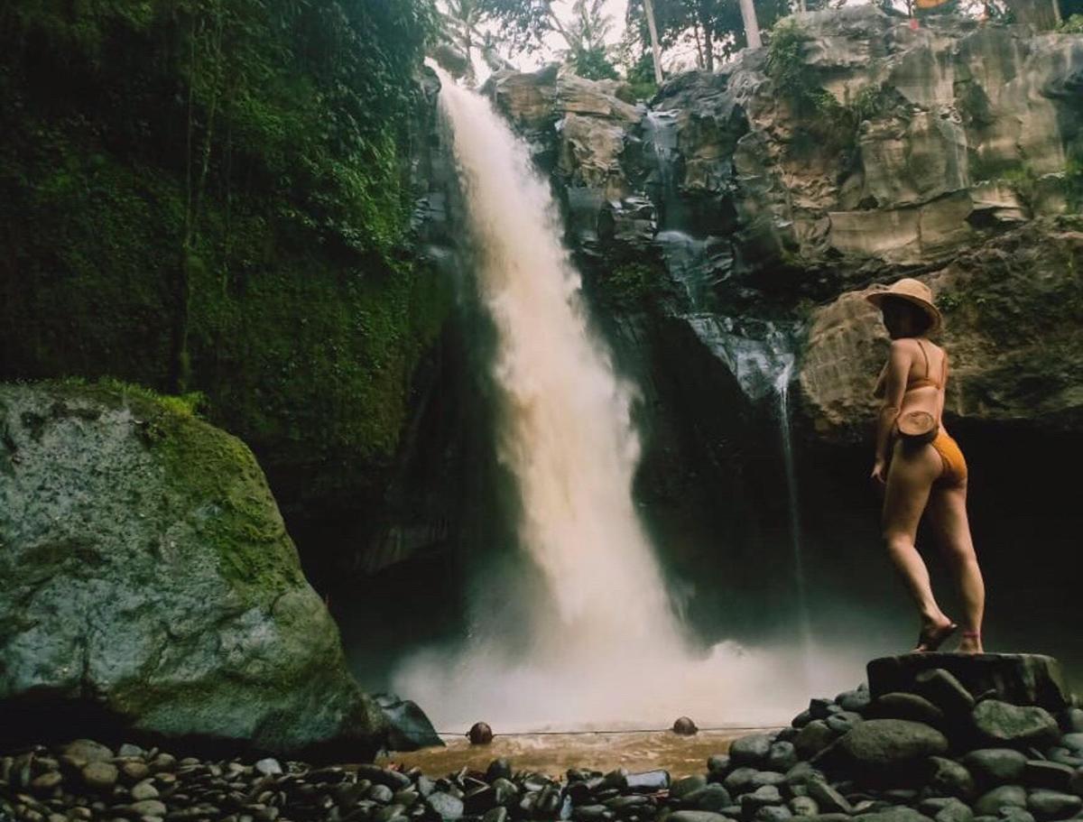 a man standing on a rock in front of a waterfall