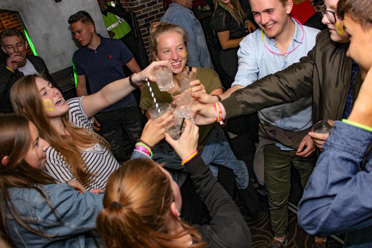 een groep mensen die hun drankjes op een feestje opheffen