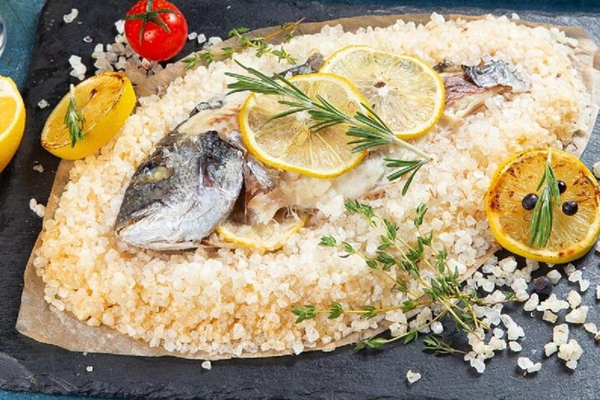 Un plato de pescado con arroz y rodajas de limón.