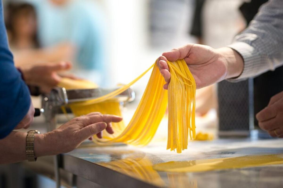 một người đang cầm một bó mì spaghetti trên bàn