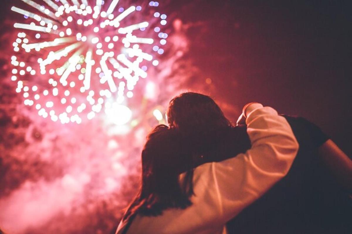 Una mujer parada frente a un espectáculo de fuegos artificiales.