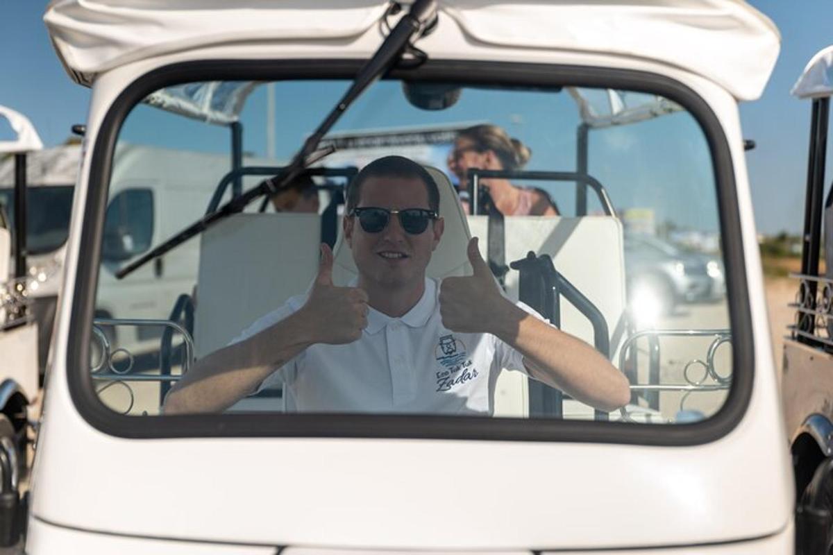 muž ukazuje palec nahoru, když sedí v golfovém vozíku