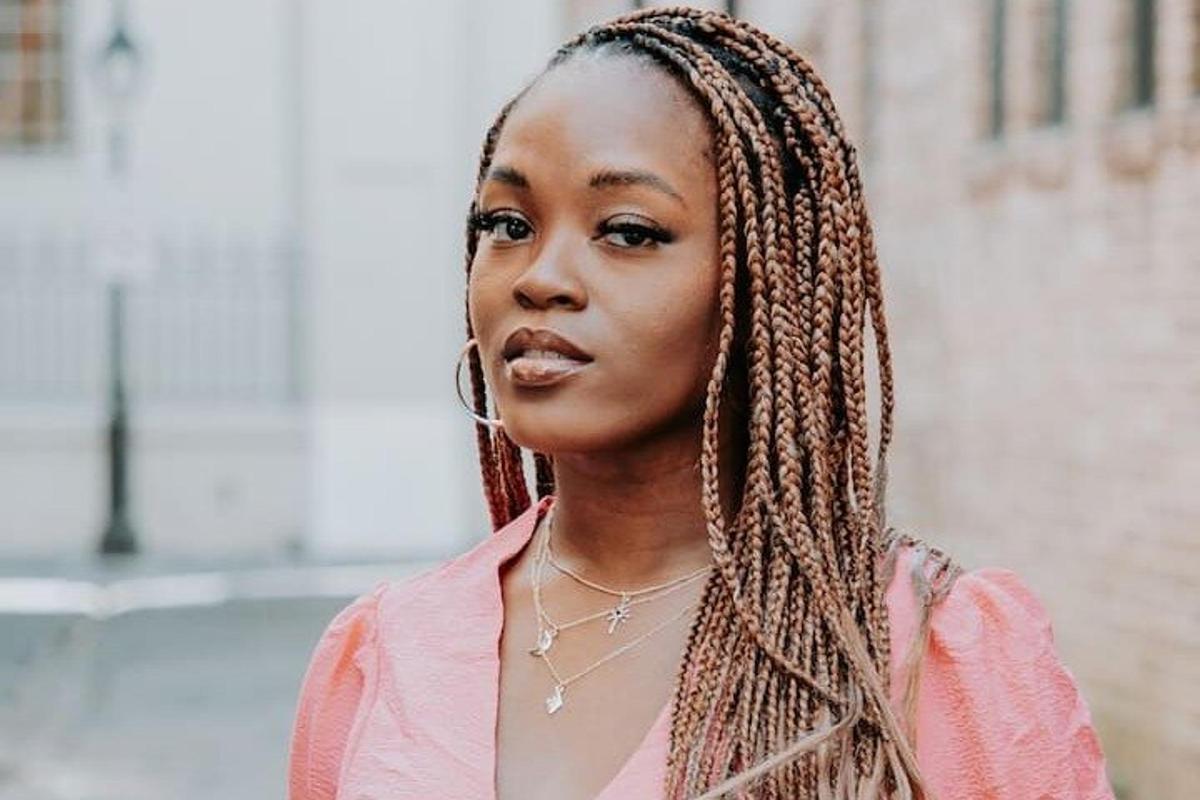 a woman with braided hair standing on a city street