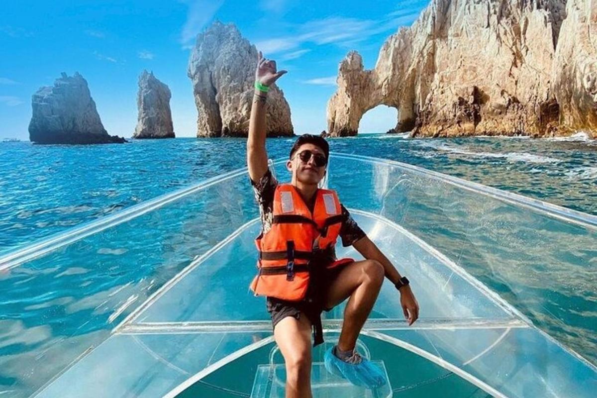 Una mujer con un chaleco salvavidas naranja en un bote de cristal en el océano.