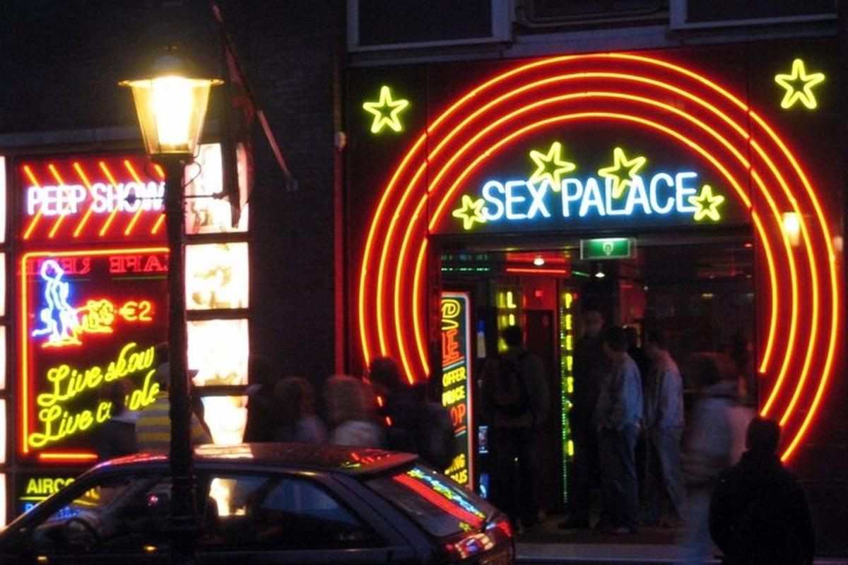 a neon sign in front of a restaurant with people standing outside